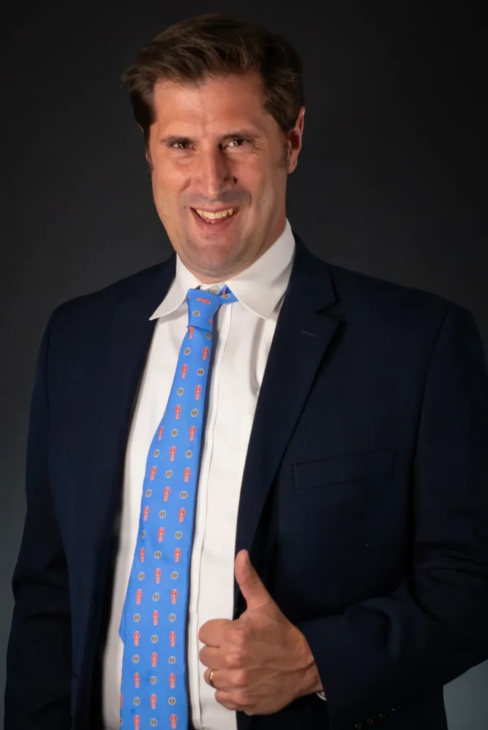 Jacob Nichols giving a thumbs up wearing a suit and a Kenworth tie.