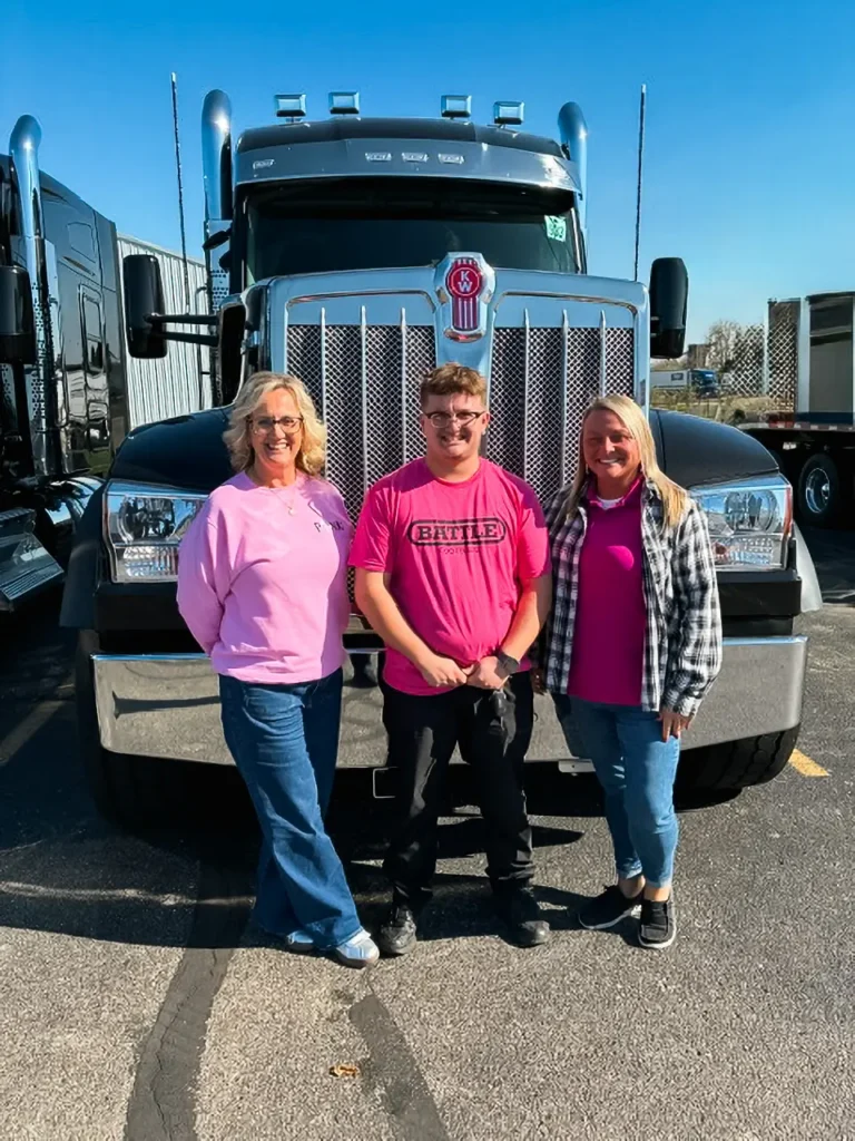 Palmer employees at Kenworth of Dayton wearing pink standing in front of a Kenworth W990