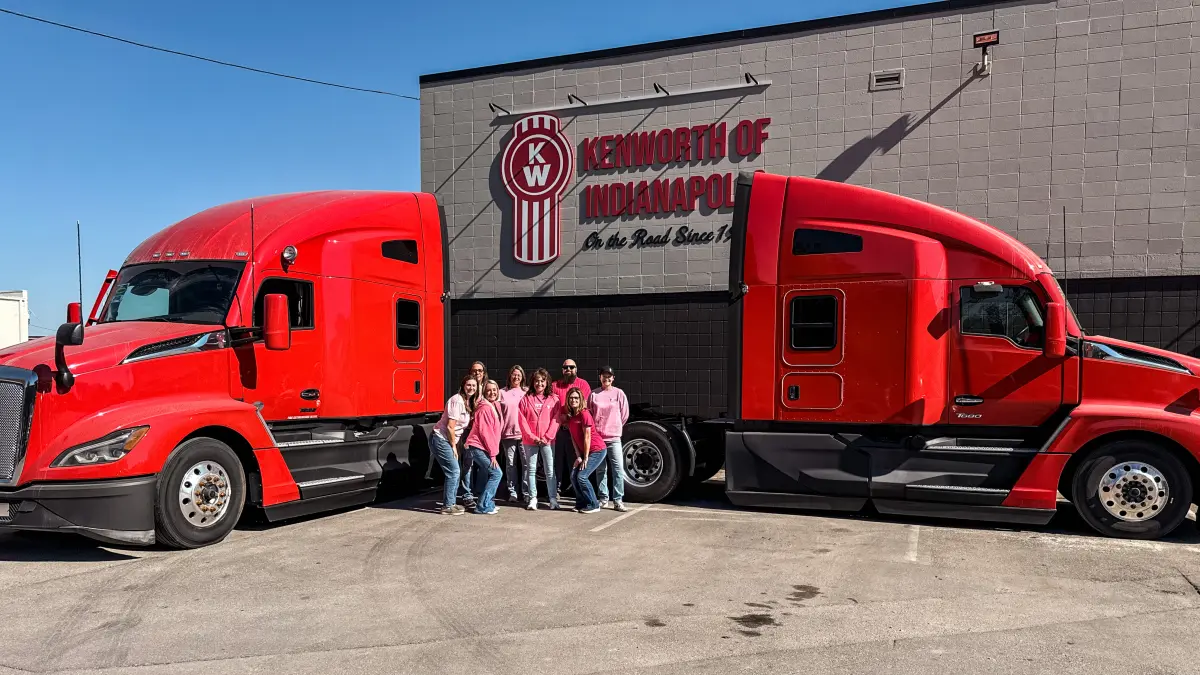 Palmer employees wearing pink and standing in between two trucks